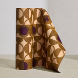 Wallpaper roll in a curvilinear art deco inspired pattern in ochre, beige and purple.