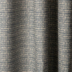 Draped linen fabric in a repeating abstract gridded pattern in navy on a cream field.