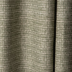 Draped linen fabric in a repeating abstract gridded pattern in sage on a cream field.