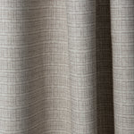 Draped linen fabric in a repeating abstract gridded pattern in beige on a cream field.
