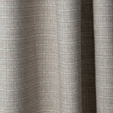 Draped linen fabric in a repeating abstract gridded pattern in beige on a cream field.