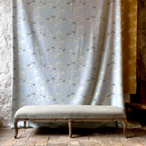 Decorative bench in front of a blue floral patterned curtain in a rustic room.