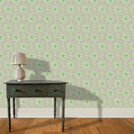 A wooden end table and lamp stand in front of a wall papered in an intricate floral lattice print in green, gray and cream.