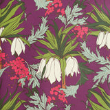 Detail of wallpaper in a dense floral print in shades of white, pink and green on a purple field.
