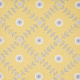 Detail of fabric in a flower and leaf lattice print in gray and white on a yellow field.