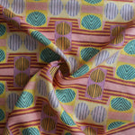 Close up of gently draped printed fabric with a complex geometric and striped pattern with pink, orange, turquoise and red. 