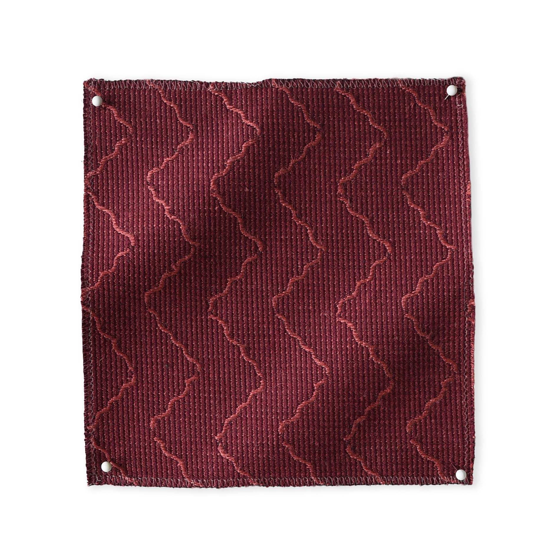 Pinned swatch of woven fabric with chevron stripe in dark red. 