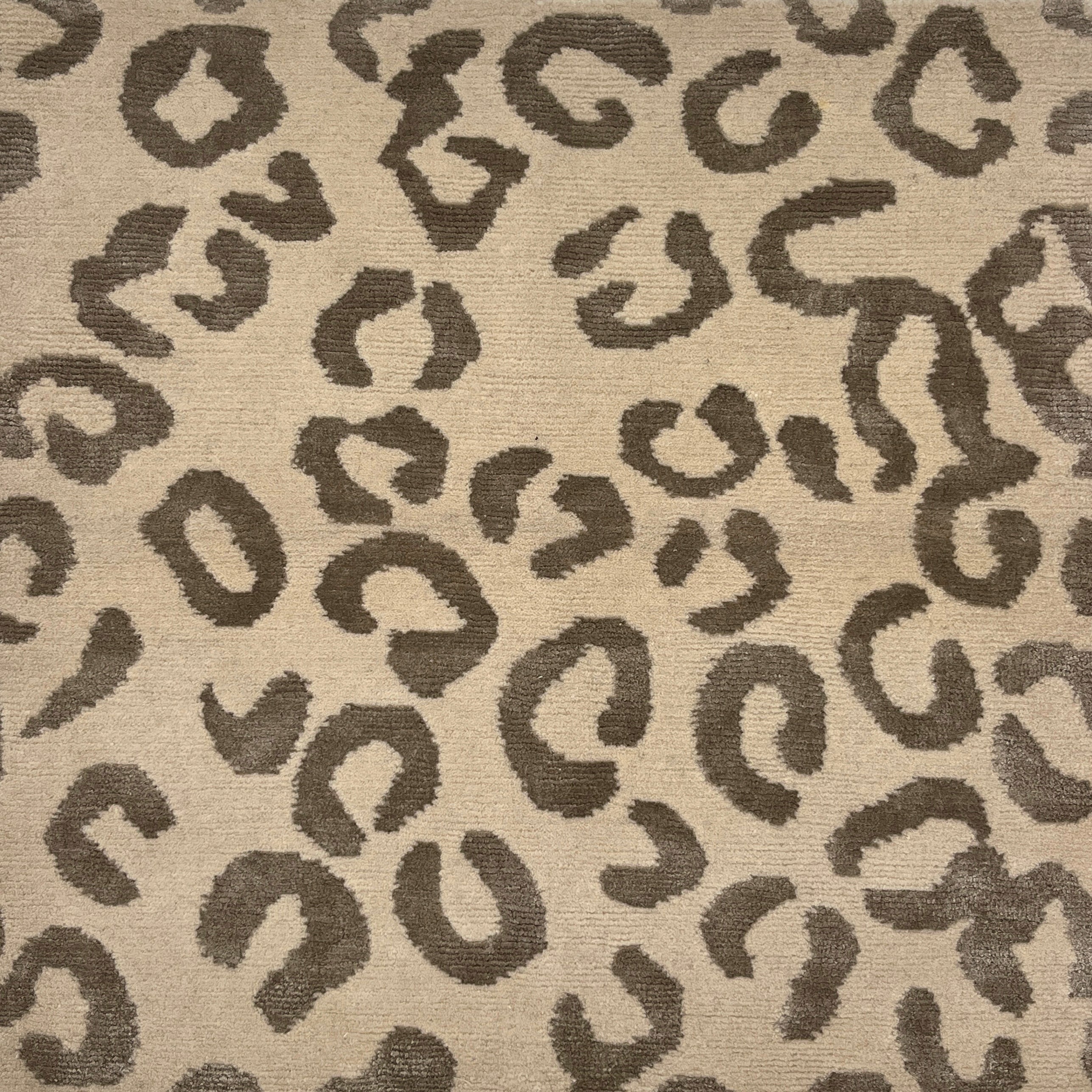 Handknotted rug with leopard spot motif in grey on cream. 