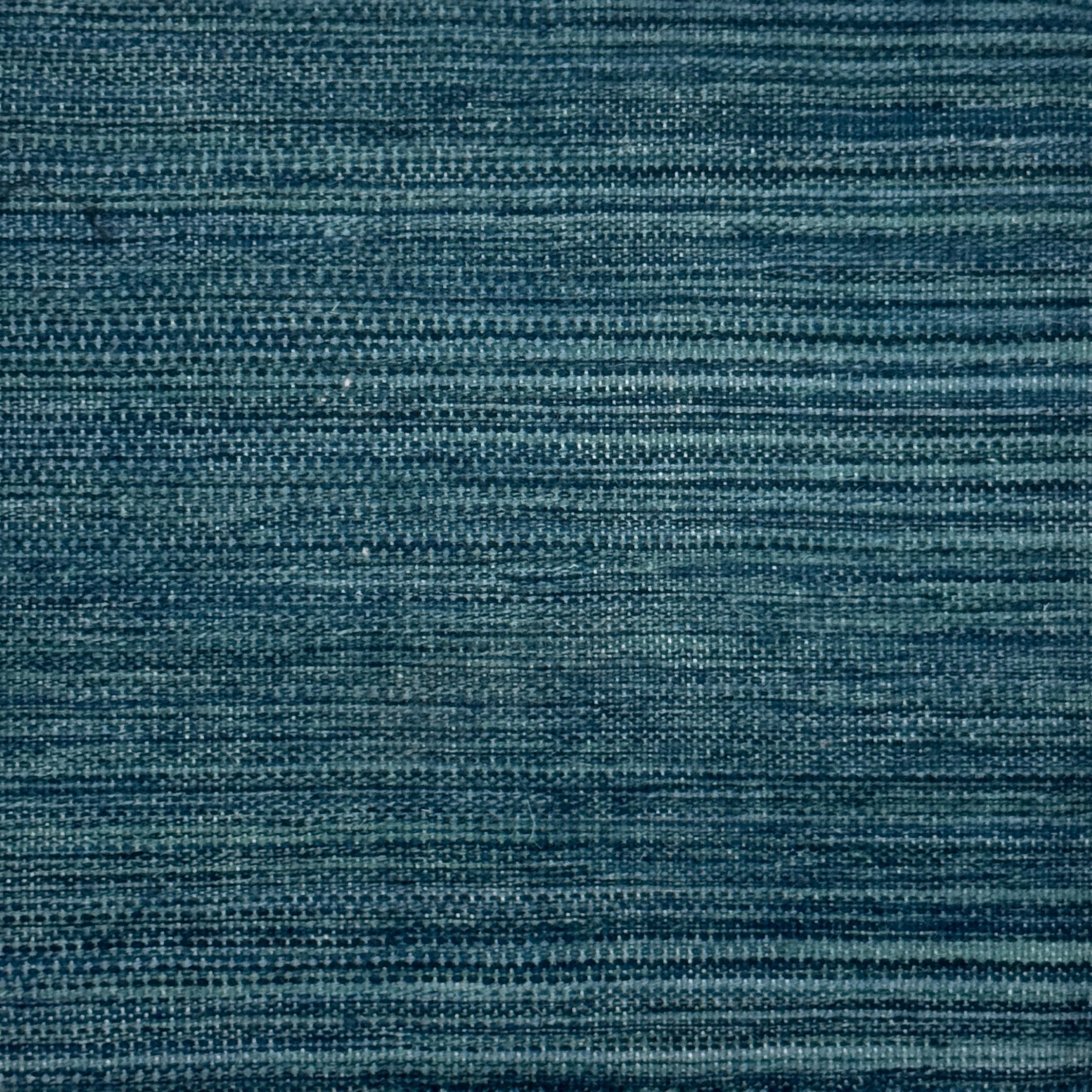 A close-up of a handwoven carpet in a heathered teal colorway. 