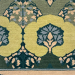 Close-up of a patterned rug with green, beige, and blue colors.