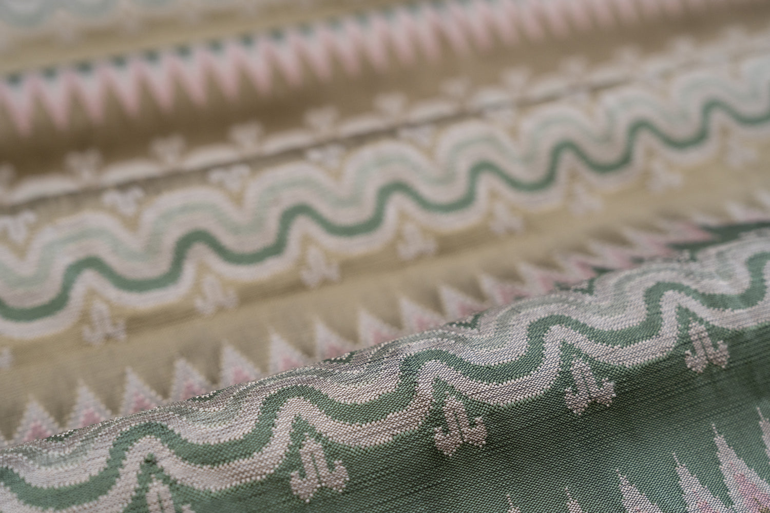 Close-up of patterned fabric with wavy lines and geometric shapes in green, tan and pink