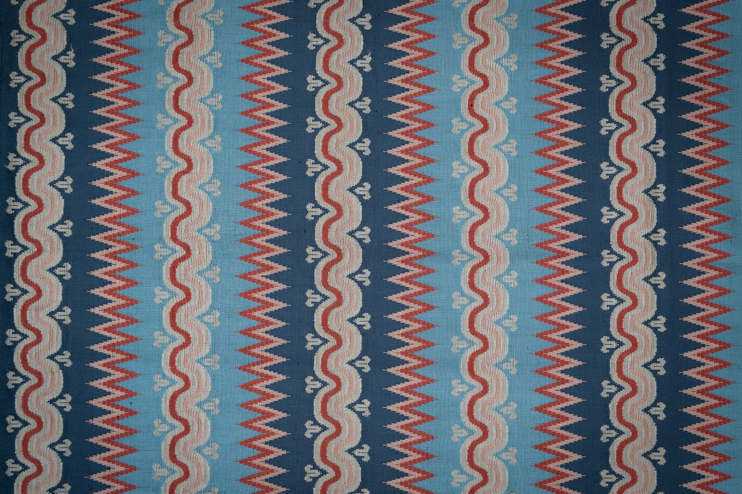 Handwoven silk fabric with zigzag and wavy designs in blue, red, and beige.