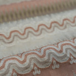 Close-up of patterned fabric with wavy lines and geometric shapes in pink, cream and beige. 