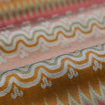 Close-up of patterned fabric with wavy lines and geometric shapes in pink, orange and red. 