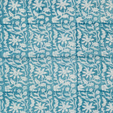 Detail of fabric in a floral block print in white on a turquoise field.