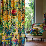A living space with long curtains and an armchair, both in the same painterly multicolor botanical print.