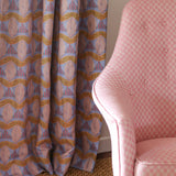 Detail of a living room with a pink checker pattern side chair, sisal rug and geometric striped leaf pattern in pink, blue and purple.
