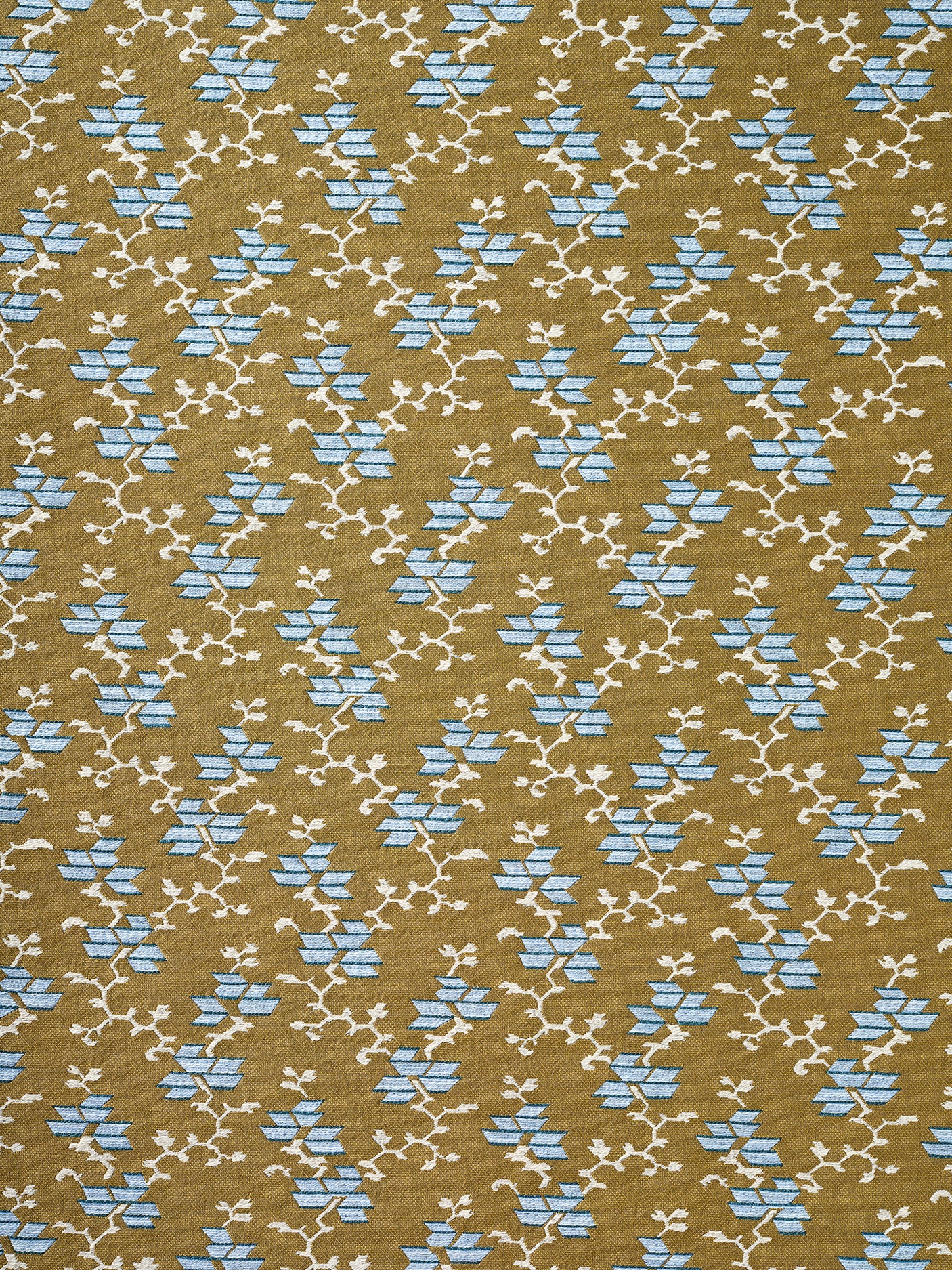 A close-up of a woven fabric pattern featuring a repeating geometric design of light blue diamond floral shapes and cream branch motifs on a warm tan background.