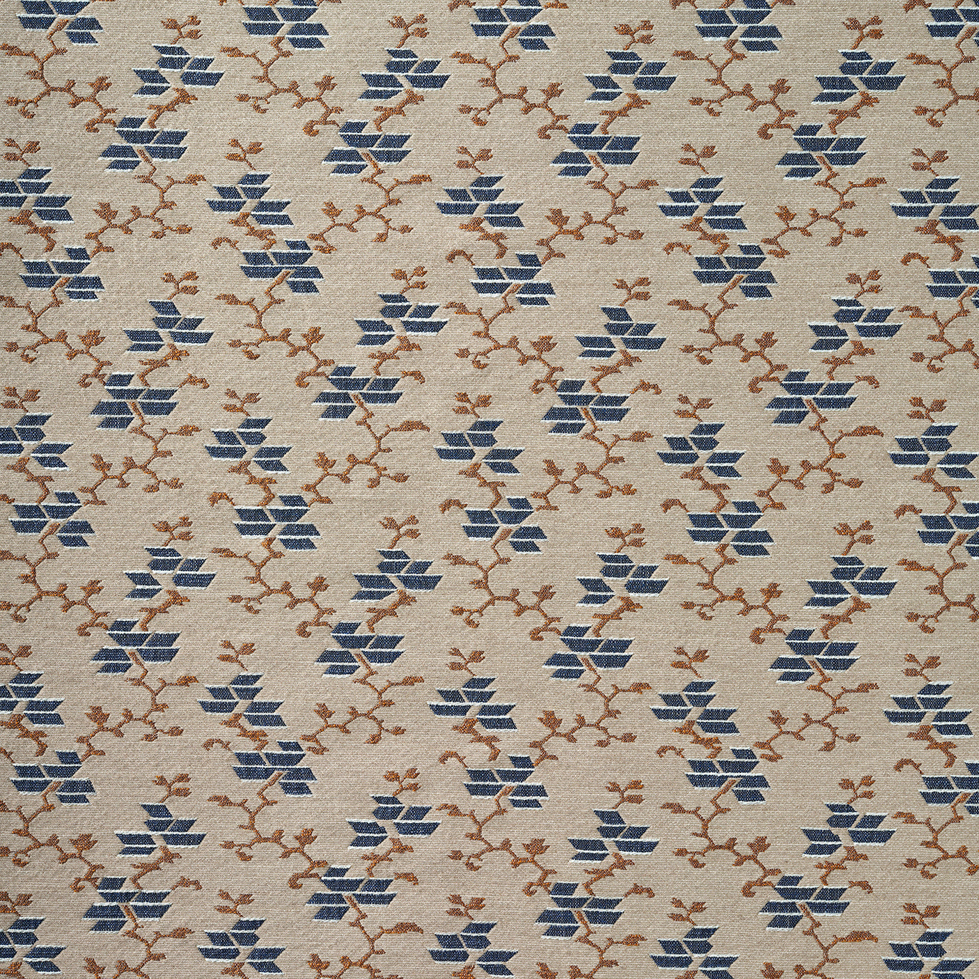 A close-up of a woven fabric pattern featuring a repeating geometric design of blue diamond floral shapes and brown branch motifs on a warm beige background.