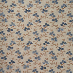 A close-up of a woven fabric pattern featuring a repeating geometric design of blue diamond floral shapes and brown branch motifs on a warm beige background.