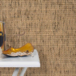 End table with a vase and sculptures in front of a wall papered in jute grasscloth.