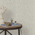 End table with a tray and some sculptures in front of a wall papered in textured grasscloth in soft white.