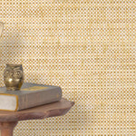 End table with a phone, book and owl sculpture in front of a wall covered in paperweave grasscloth in checked cream and tan.