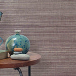 End table with a vase, horse sculpture and stones in front of a wall covered in sisal grasscloth in cream and maroon.