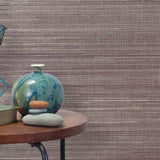 End table with a vase, horse sculpture and stones in front of a wall covered in sisal grasscloth in cream and maroon.