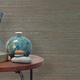 End table with a vase, horse sculpture and stones in front of a wall covered in sisal grasscloth in blue and brown.