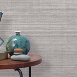 End table with a vase, horse sculpture and stones in front of a wall covered in sisal grasscloth in mottled gray.