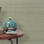 End table with a vase, horse sculpture and stones in front of a wall covered in sisal grasscloth in cream and green.