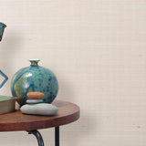 End table with a vase, horse sculpture and stones in front of a wall covered in sisal grasscloth in mottled pink.