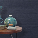 End table with a vase, horse sculpture and stones in front of a wall covered in sisal grasscloth in mottled navy.
