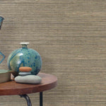 End table with a vase, horse sculpture and stones in front of a wall covered in sisal grasscloth in mottled tan and black.