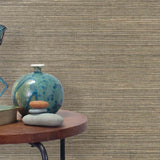 End table with a vase, horse sculpture and stones in front of a wall covered in sisal grasscloth in mottled tan and black.