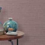 End table with a vase, horse sculpture and stones in front of a wall covered in sisal grasscloth in mottled mauve.