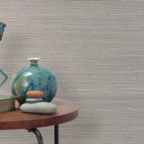 End table with a vase, horse sculpture and stones in front of a wall covered in sisal grasscloth in mottled gray.