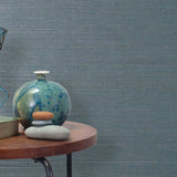 End table with a vase, horse sculpture and stones in front of a wall covered in sisal grasscloth in gray and blue-green.