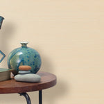End table with a vase, horse sculpture and stones in front of a wall covered in sisal grasscloth in cream.