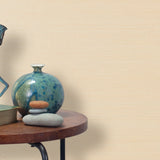 End table with a vase, horse sculpture and stones in front of a wall covered in sisal grasscloth in cream.