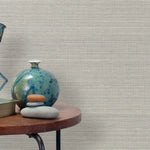 End table with a vase, horse sculpture and stones in front of a wall covered in sisal grasscloth in white and gray.