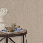 End table with a tray and some sculptures in front of a wall papered in textured grasscloth in brown.