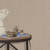 End table with a tray and some sculptures in front of a wall papered in textured grasscloth in brown.
