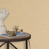 End table with a tray and some sculptures in front of a wall papered in textured grasscloth in cream. 