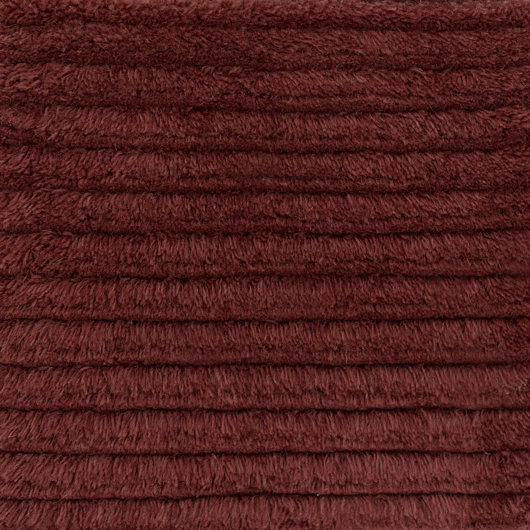 Close up of a shag stripe carpet in deep red. 