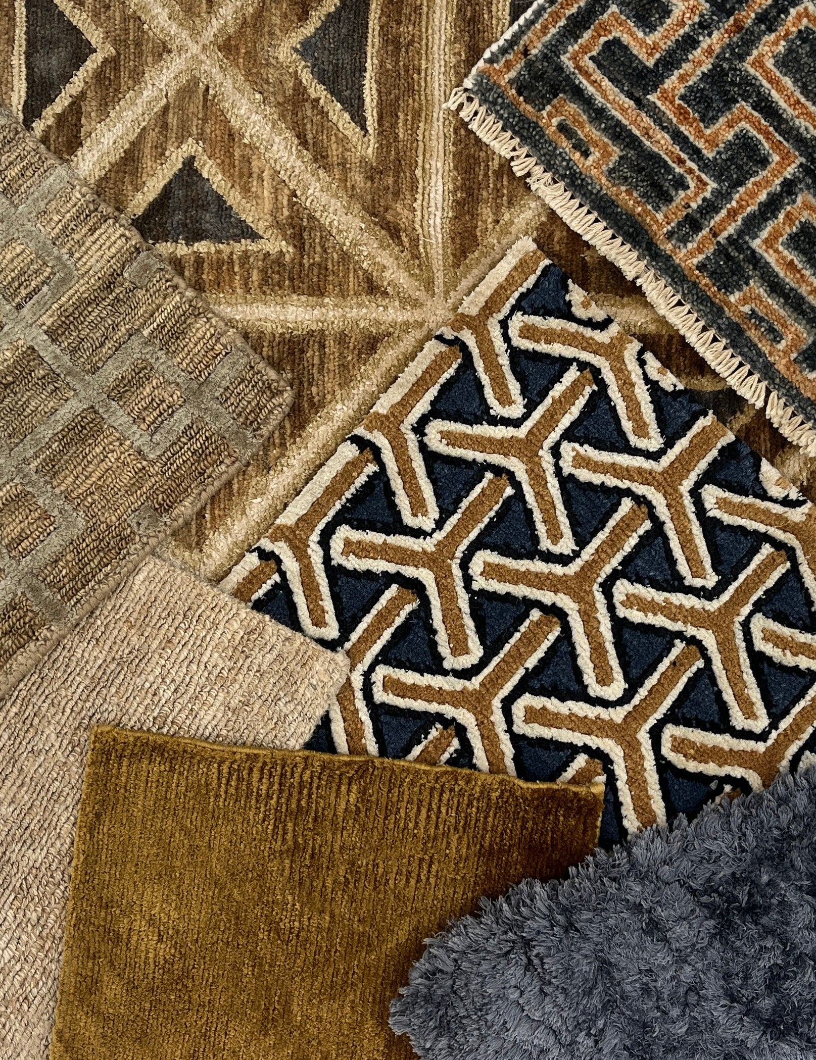 Styled flat lay image with handmade rugs in geometric patterns and solid textures in navy blue, taupe and beige. 