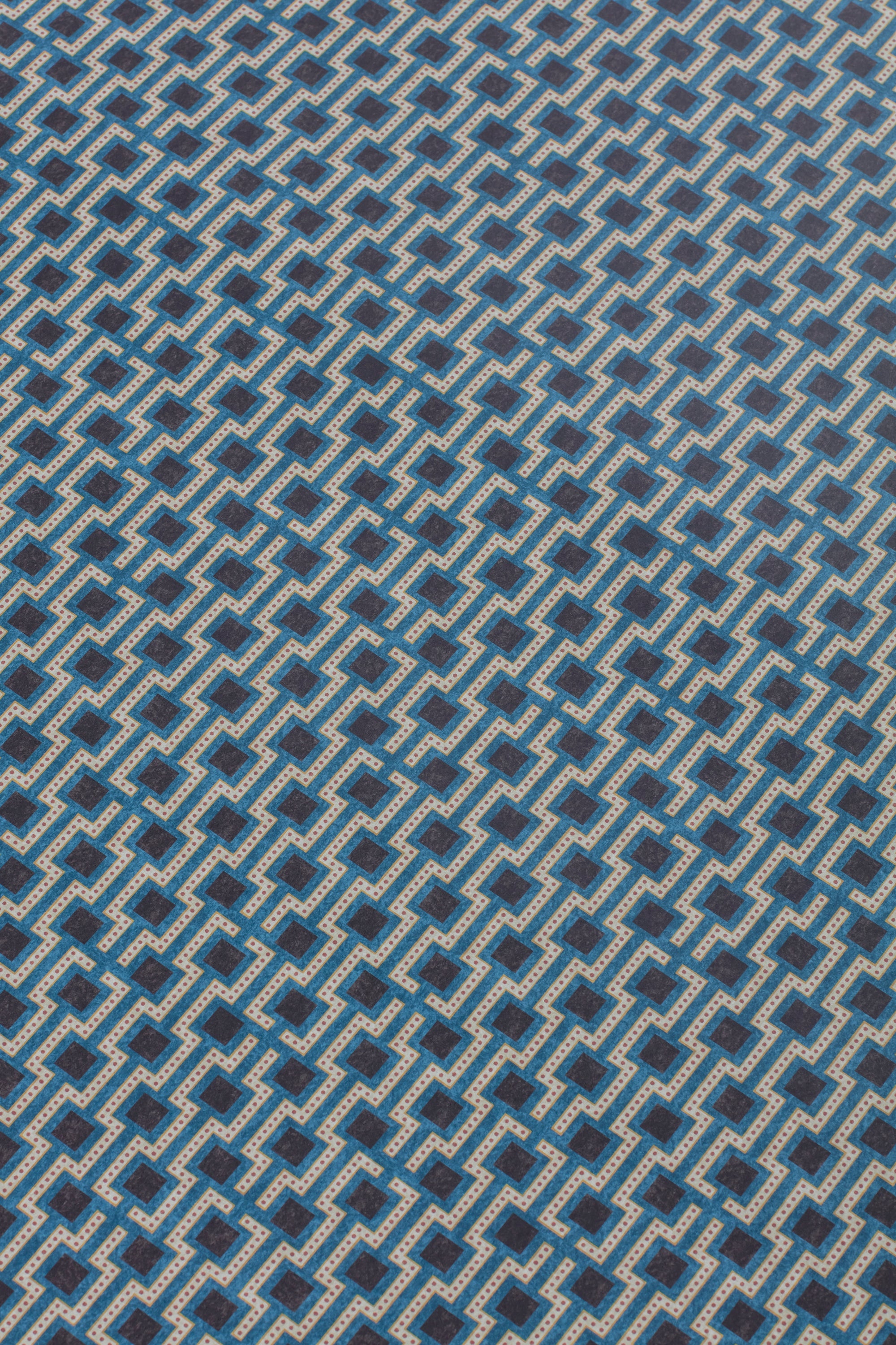 Detail of a wallpaper panel in a geometric grid print in shades of blue, red, navy and cream.