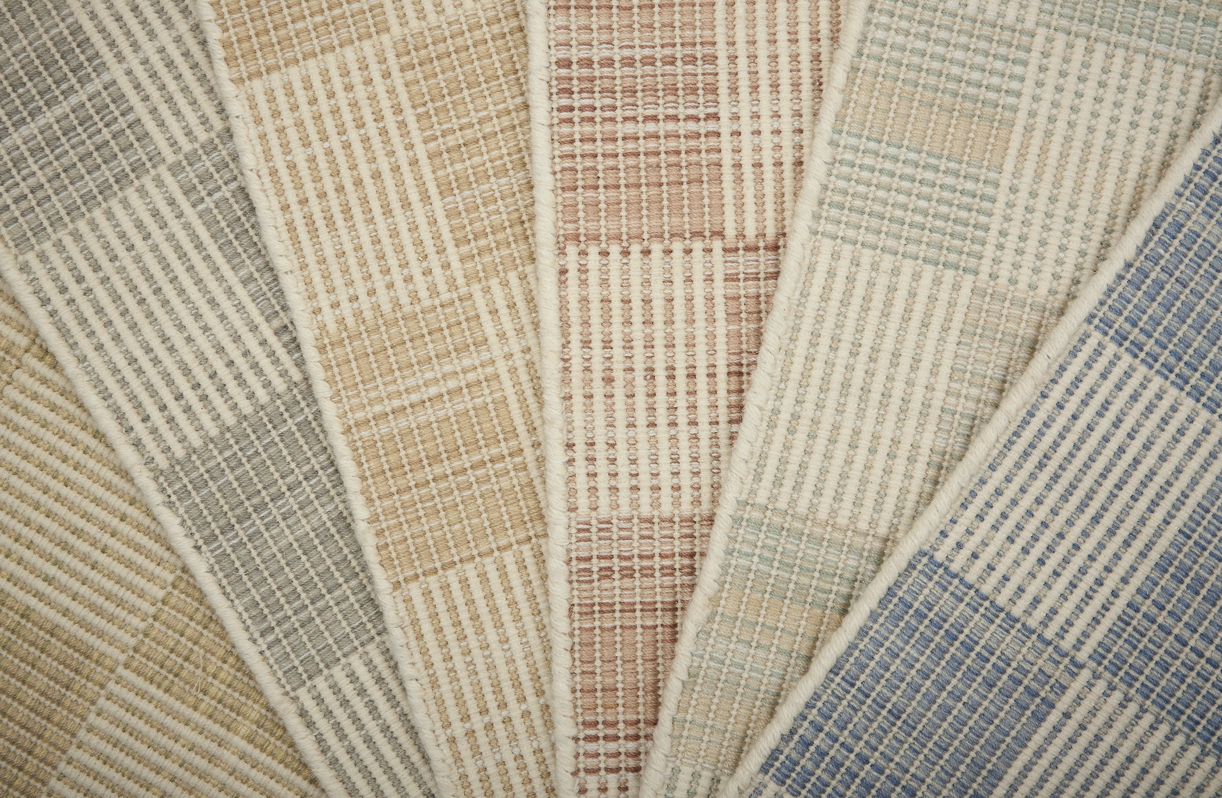 Stack of broadloom samples in a checkerboard pattern in cream and pastel hues.