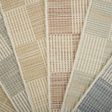 Stack of broadloom samples in a checkerboard pattern in cream and pastel hues.